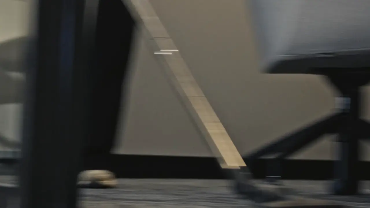 A vacuum head moving under a meeting table and desks in an office, motion blurred mid pass